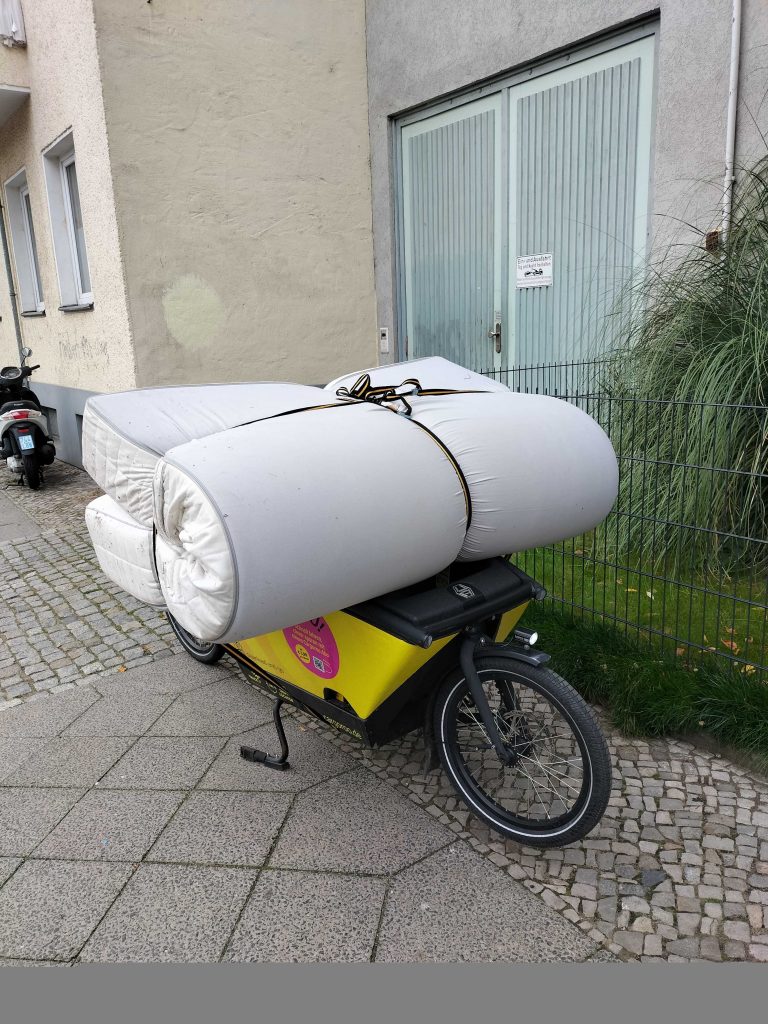 Lastenrad Cargoroo beladen mit einer Matratze aus verschiedenen Blickwinkeln.